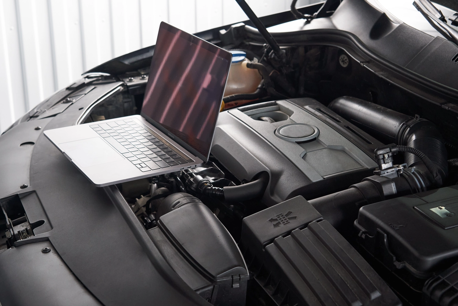 Fuhrparkservice Mobil14 – Beratung, Planung & Wartung für Nutzfahrzeugflotten – Das Bild zeigt einen Laptop im Motorraum eines modernen Autos. Diese gängige Konfiguration wird für die Fahrzeugdiagnose und die Optimierung des elektronischen Steuergeräts (ECU) verwendet.