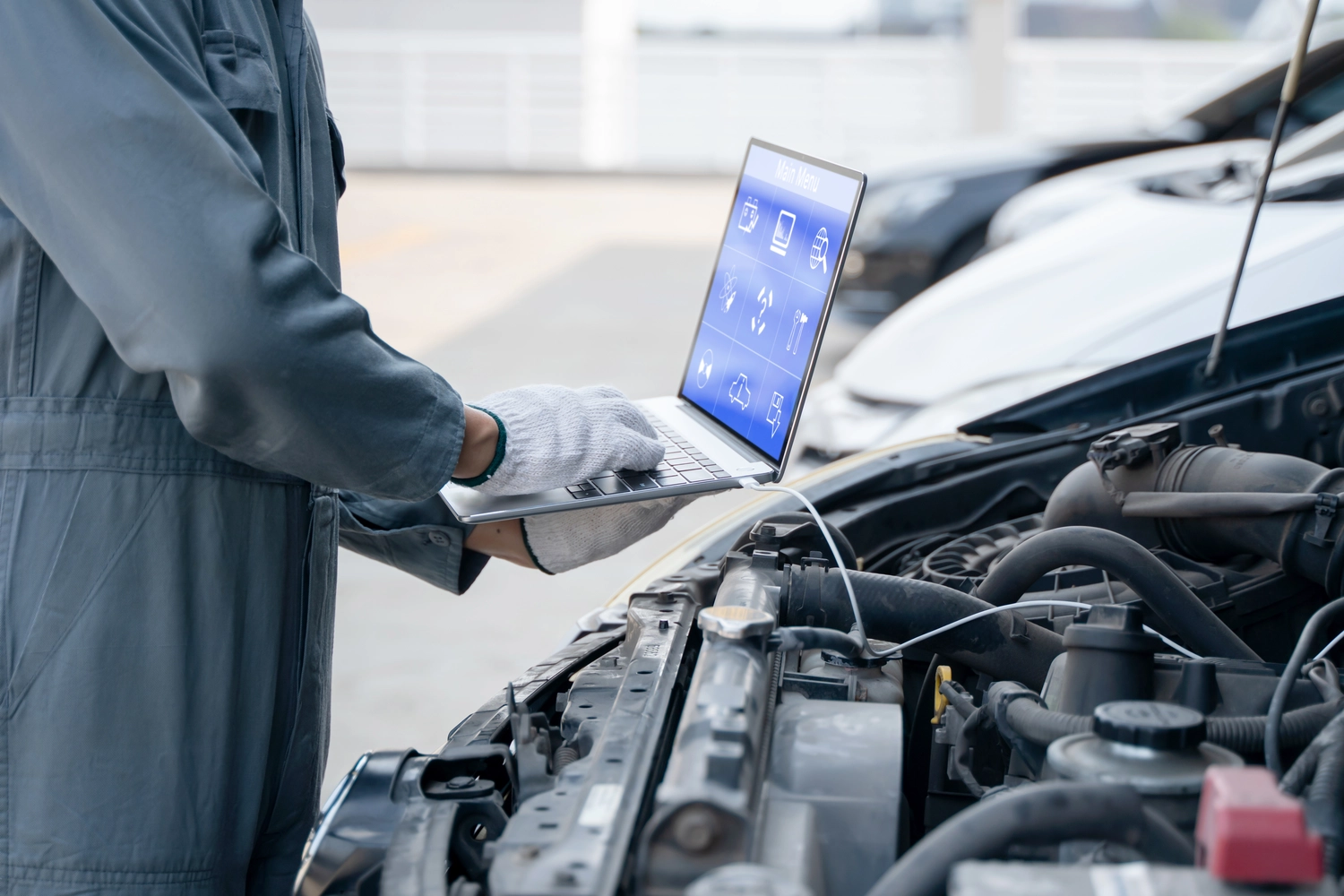 Fuhrparkservice Mobil14 – Beratung, Planung & Wartung für Nutzfahrzeugflotten – Dieses Bild zeigt eine Fahrzeugdiagnose, bei der ein Mechaniker mit einem Laptop Probleme am Motor identifiziert und behebt.